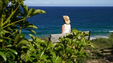 Bärbel von YOGAMOUR Meditiert auf einer Bank mit Blick auf das Meer
