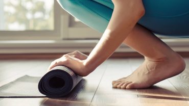 Person rollt eine Yogamatte: YOGAMOUR Yoga-Workshop